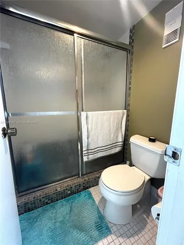a white toilet sitting next to a shower