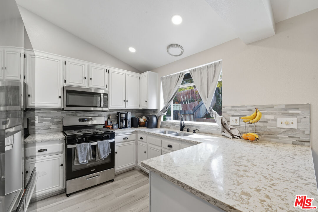 2048 East Ave R 10 Palmdale, CA 93550 - Photo 17 of 45 a kitchen with a sink a stove and cabinets
