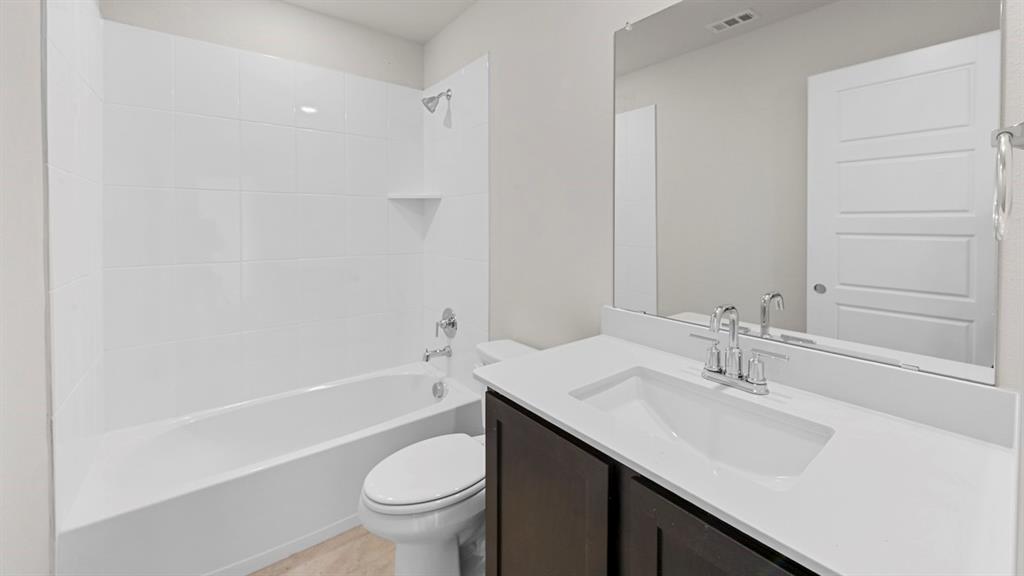 412 Carthage Street Caddo Mills, TX 75135 - Photo 5 of 32 Bathroom featuring a white subway tile shower surround with a built-in corner shelf, a white bathtub, and a modern vanity with a rectangular sink, chrome faucet, and dark wood-finish cabinetry