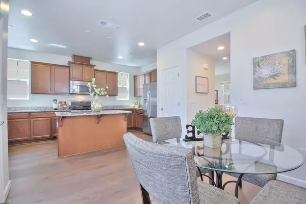 a kitchen with granite countertop kitchen island stainless steel appliances a refrigerator and a dining table