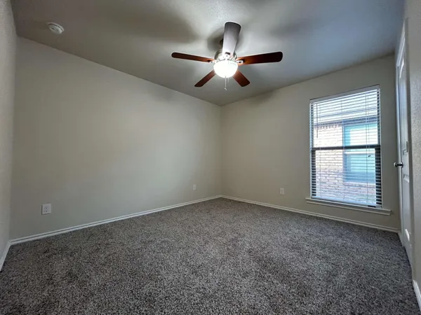 an empty room with chandelier fan and windows