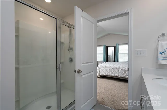 a en suite bathroom with a granite countertop shower a sink and a mirror
