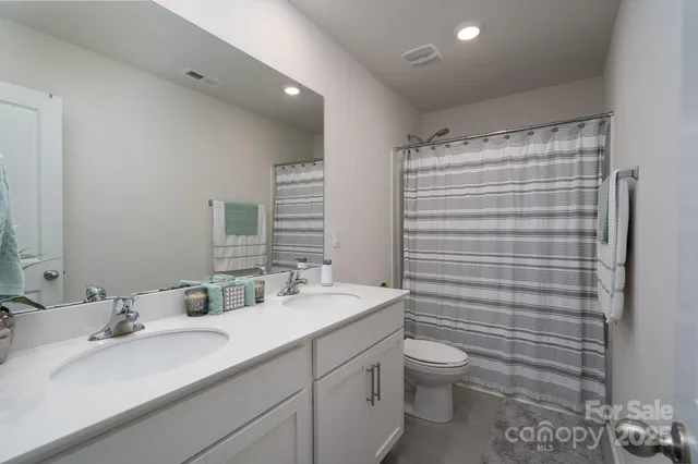 a bathroom with a double vanity sink toilet and a mirror