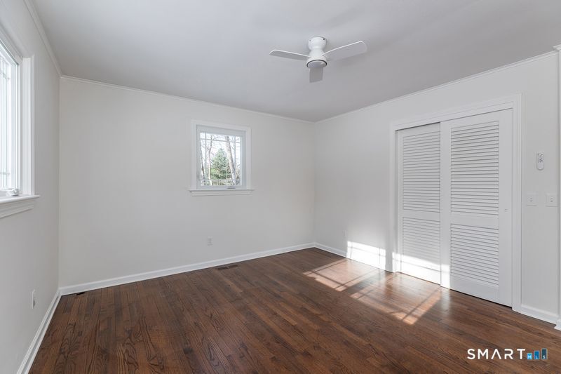 an empty room with wooden floor chandelier fan and windows