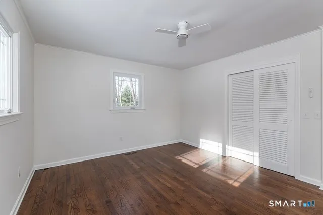 an empty room with wooden floor chandelier fan and windows