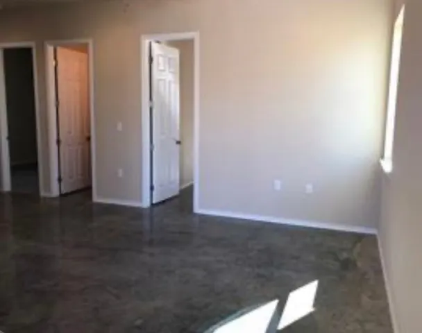 an empty room with wooden floor & windows