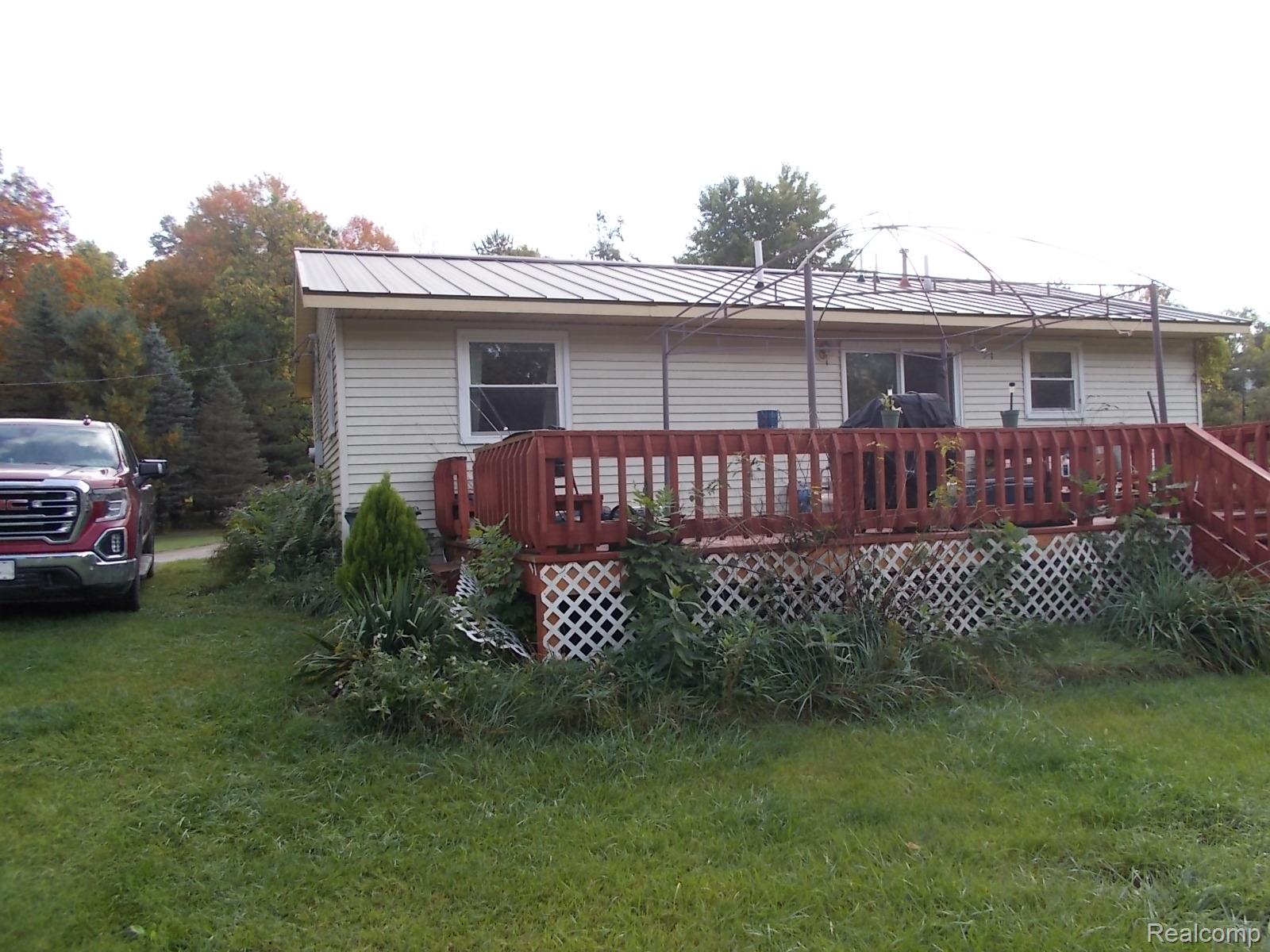 3130 Cat Lake Road Caro, MI 48723 - Photo 2 of 11 Siding exterior with a metal roof and a spacious wood-finish deck featuring lattice skirting