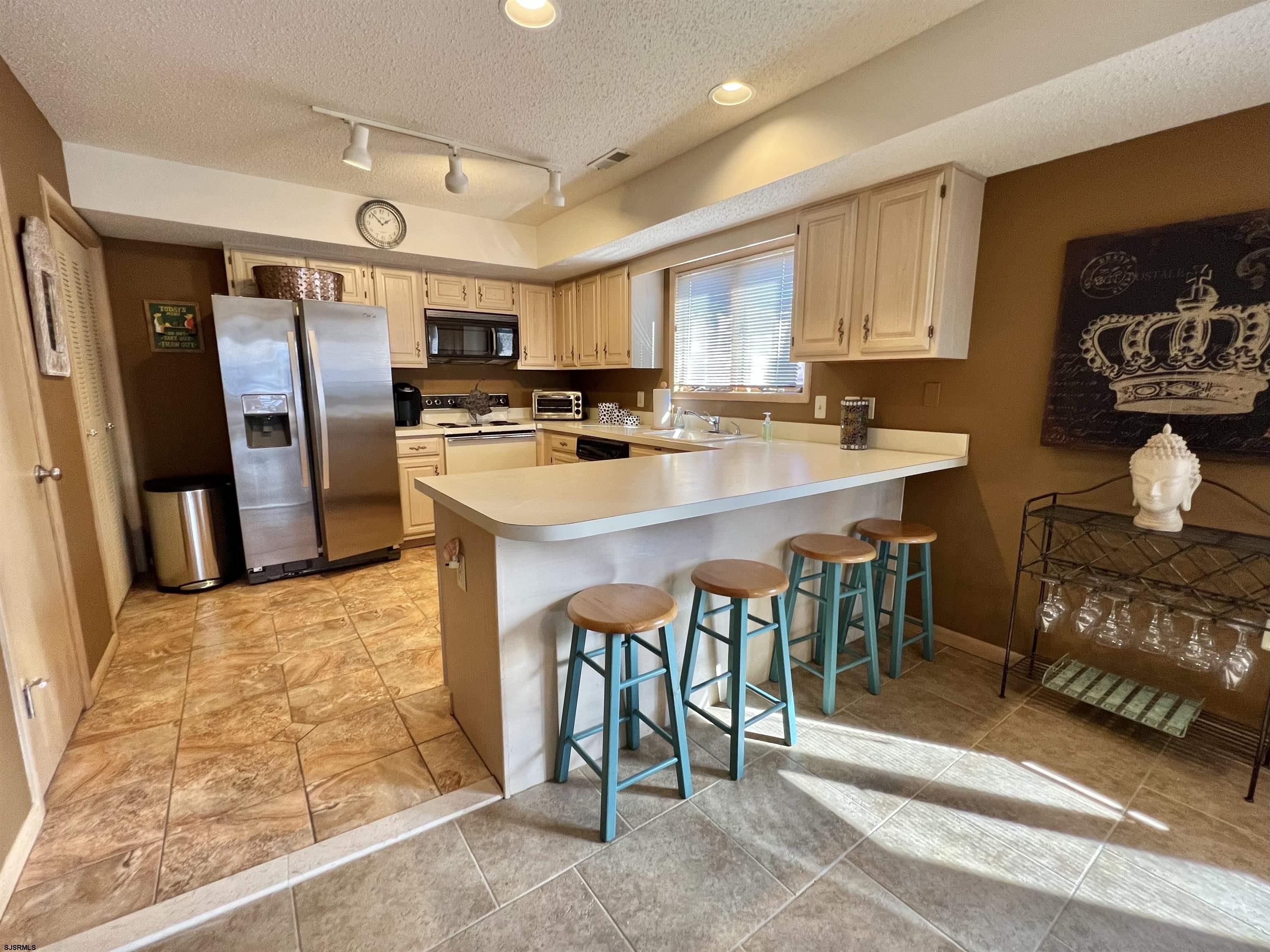 211 3rd Street North, Unit B Brigantine, NJ 08203 - Photo 20 of 52 a kitchen with stainless steel appliances kitchen island granite countertop a table chairs sink and refrigerator