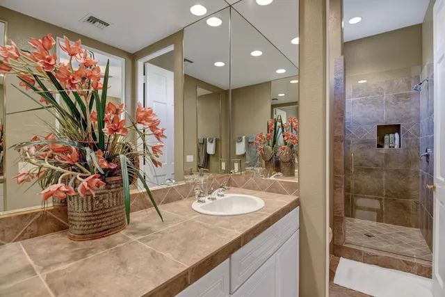 a bathroom with a granite countertop sink a mirror and a shower