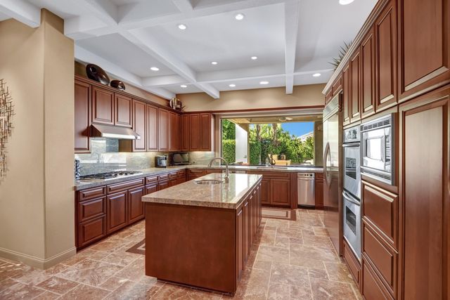 a kitchen with stainless steel appliances granite countertop a refrigerator a sink a stove and a refrigerator