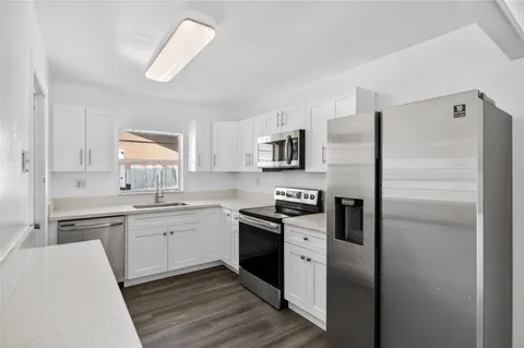 a kitchen with white cabinets and sink