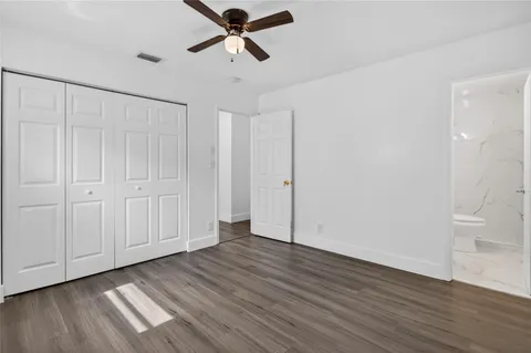 an empty room with wooden floor and ceiling fan