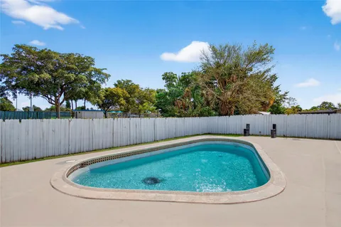 a view of a backyard with swimming pool and wooden fence