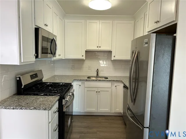 a kitchen with stainless steel appliances granite countertop a refrigerator stove top oven and sink