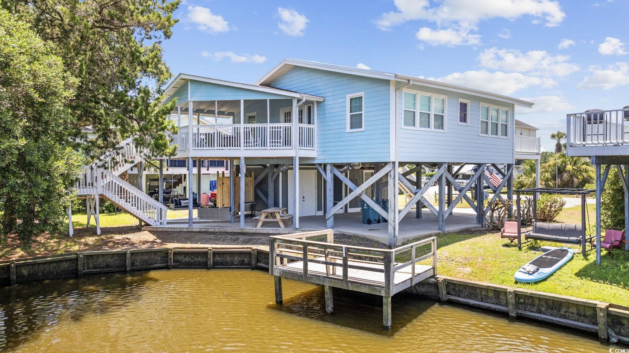 222 Calhoun Drive Murrells Inlet, SC 29576 - Photo 40 of 40 Rear view of house featuring a water view, a patio area, a sunroom, and a lawn