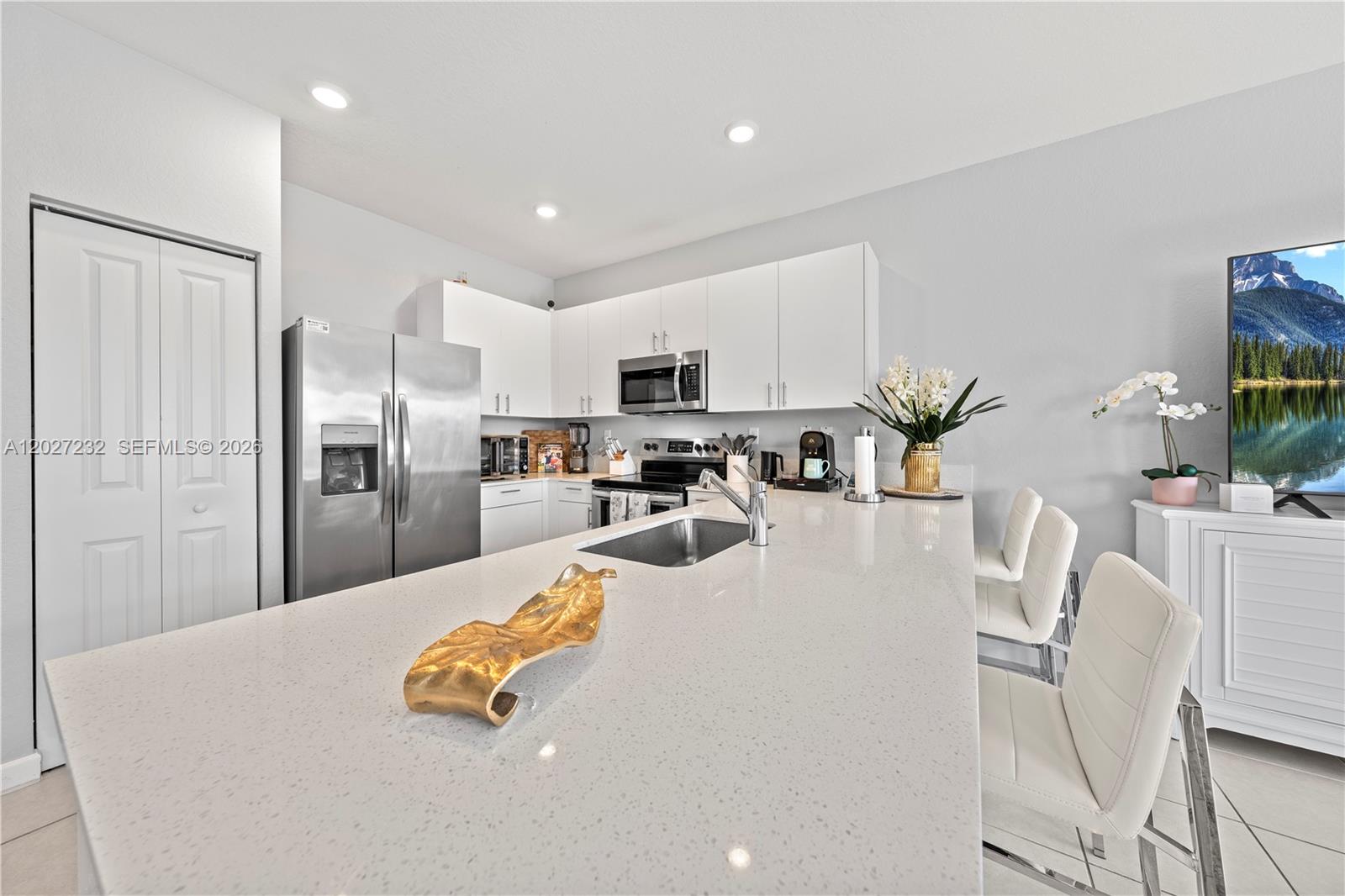 23489 Southwest 127th Place Homestead, FL 33032 - Photo 8 of 24 a kitchen with stainless steel appliances granite countertop a refrigerator a stove a sink a dining table and chairs with wooden floor