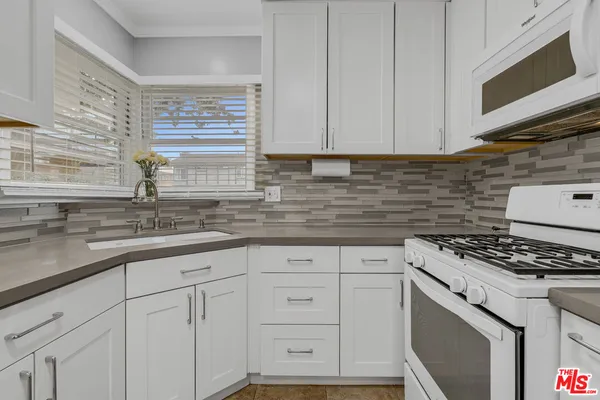 a kitchen with granite countertop white cabinets and white appliances