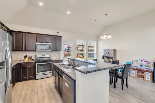 a kitchen with granite countertop kitchen island stainless steel appliances a stove a sink a refrigerator a center island and furniture