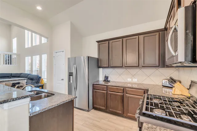 a kitchen with stainless steel appliances granite countertop a stove a sink and a refrigerator