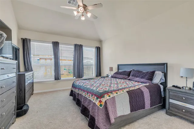 a bedroom with a large bed and a flat tv screen on dresser