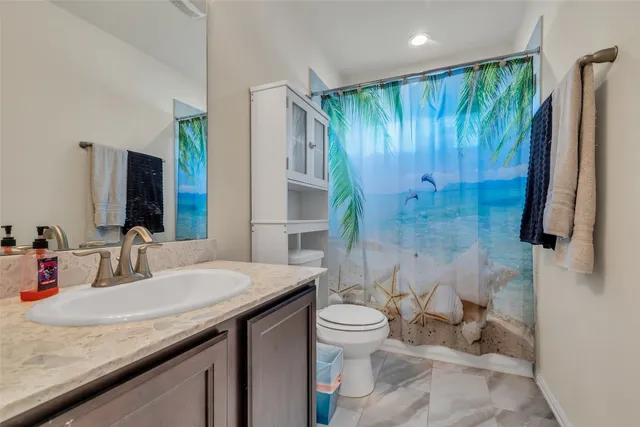 a bathroom with a granite countertop sink toilet and shower