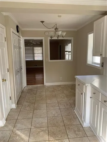 an empty room with wooden floor chandelier and windows