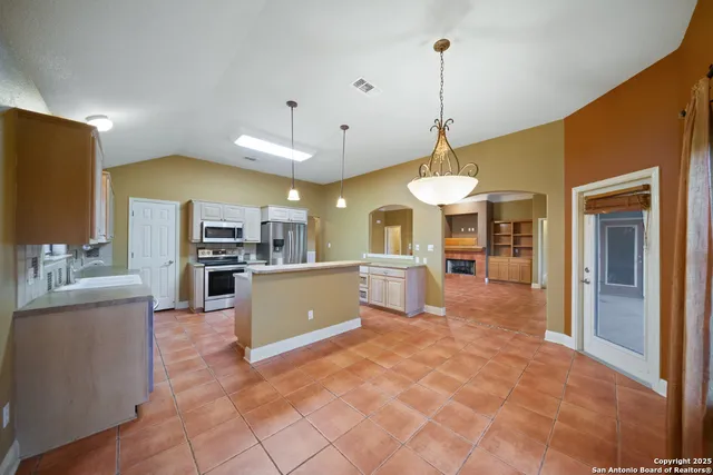 a large kitchen with a counter space a sink appliances and cabinets
