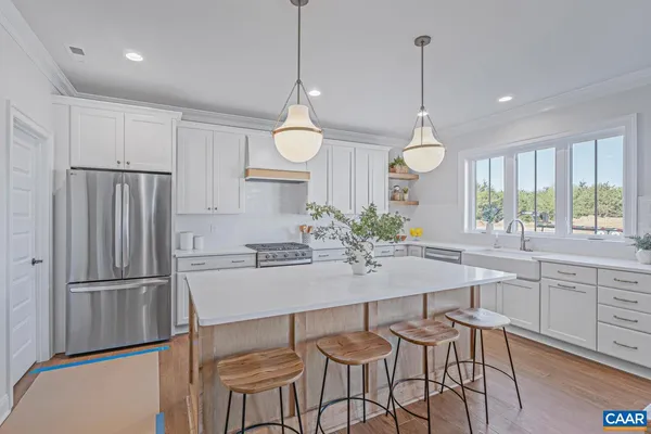 a kitchen with granite countertop a refrigerator a stove a sink and chairs