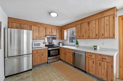 a kitchen with a refrigerator a stove a sink dishwasher and wooden cabinets