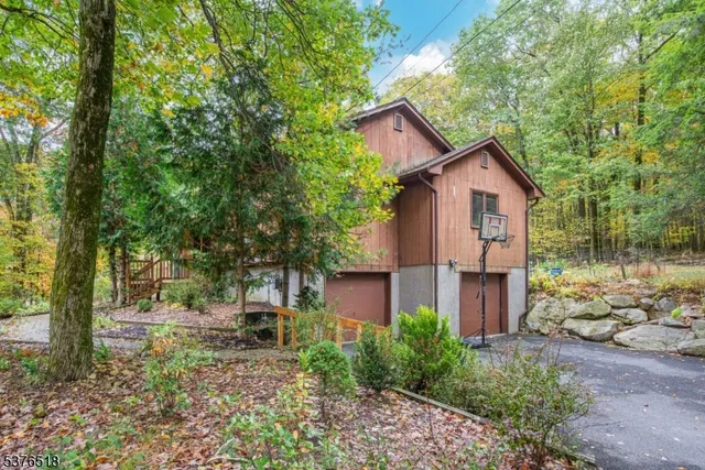 a view of a brick house with large trees and plants