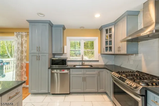 a kitchen with stainless steel appliances granite countertop a stove a sink and a microwave