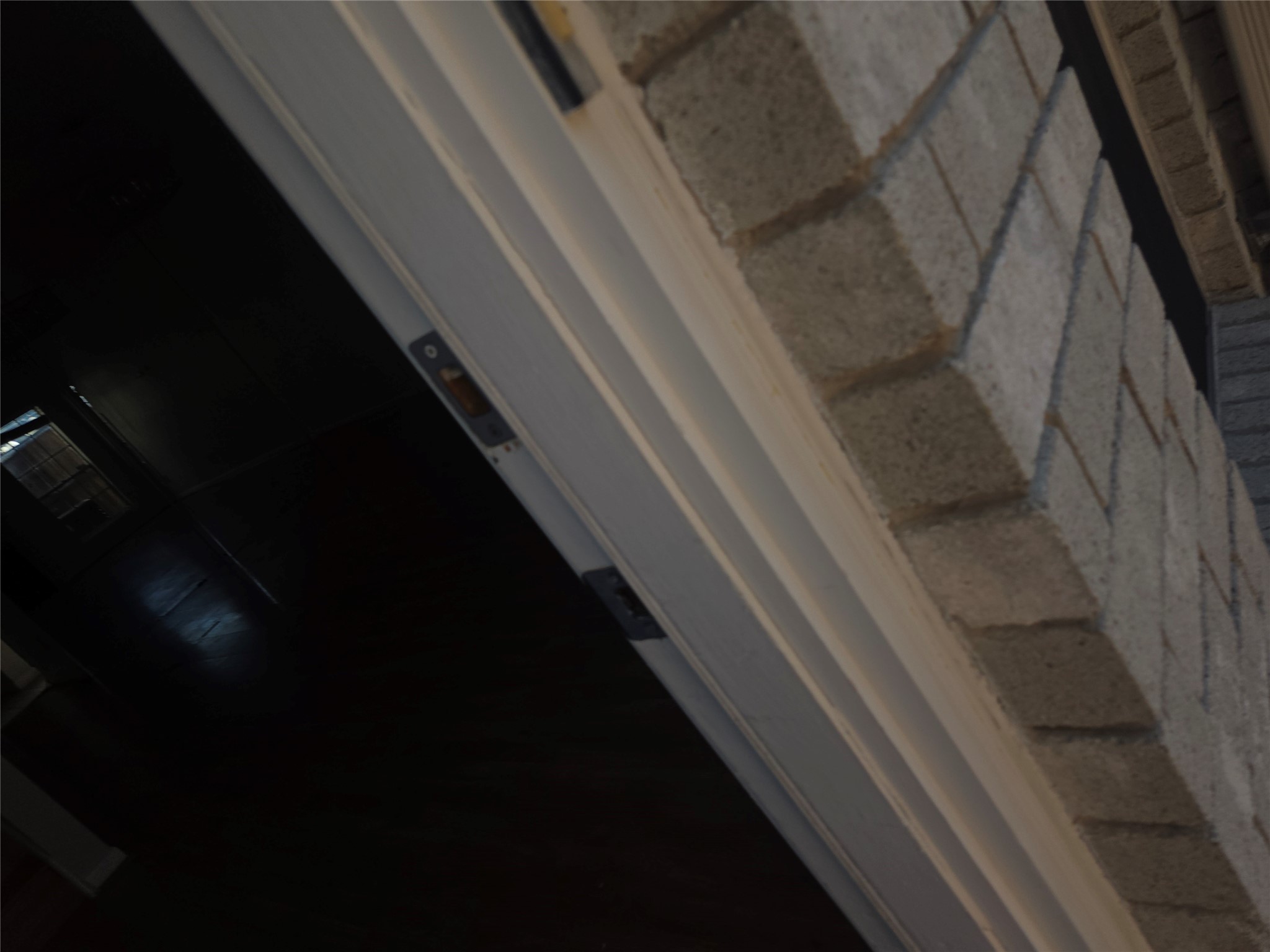 3780 Tanglewilde Street, Unit 501 Houston, TX 77063 - Photo 22 of 26 This image shows a close-up of a partially open door with a brick exterior wall, leading into a dimly lit interior space.