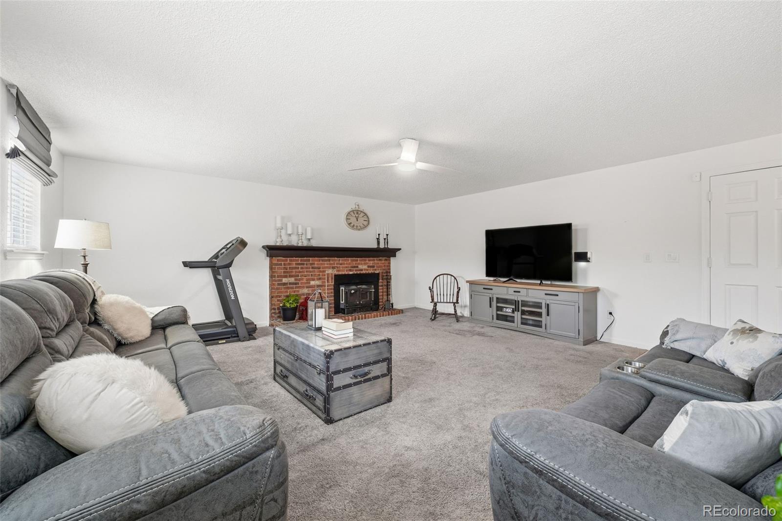 4993 East 111th Place Thornton, CO 80233 - Photo 12 of 50 a living room with furniture a flat screen tv and a fireplace