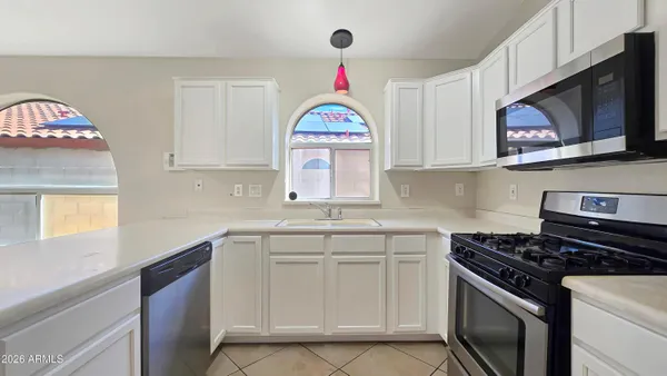 a kitchen with stainless steel appliances granite countertop a sink dishwasher a stove and a microwave oven with cabinets