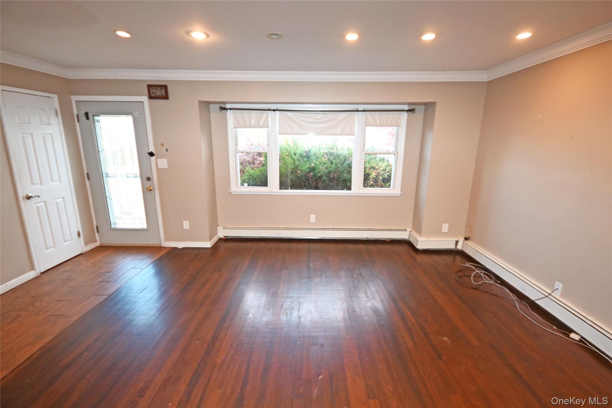 89 Osborne Road West Hempstead, NY 11552 - Photo 19 of 50 Spare room featuring crown molding, dark wood-style flooring, recessed lighting, and a baseboard heating unit