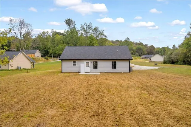 a view of a house with a yard and a large tree