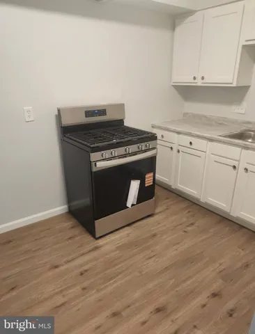 a kitchen with granite countertop a stove and a wooden floors