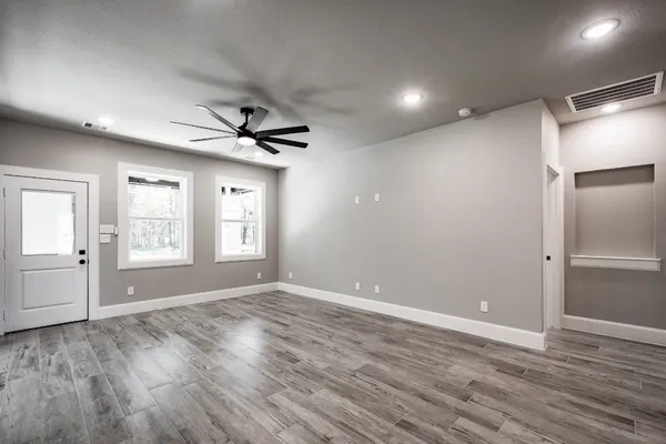 a view of empty room with wooden floor and fan