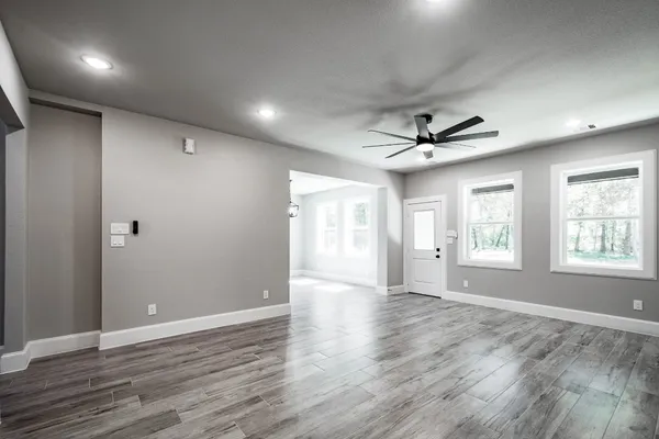a view of an empty room with wooden floor and a window