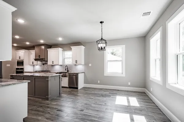 a kitchen with stainless steel appliances kitchen island granite countertop a sink cabinets a stove and a window