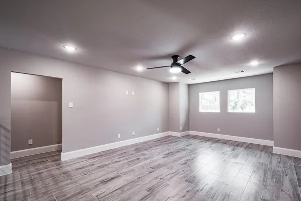 a view of an empty room with wooden floor and a window