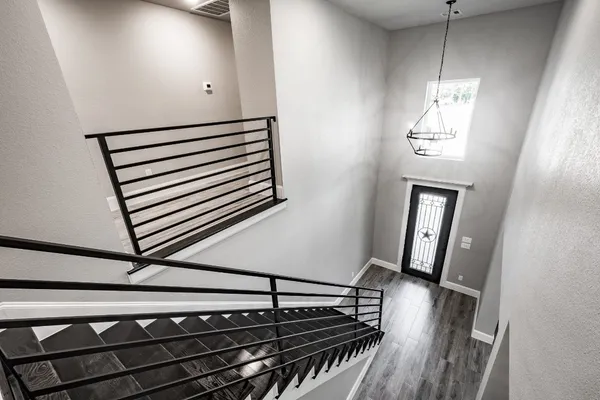 a view of a hallway with wooden floor and a chandelier