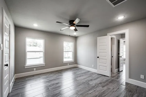 an empty room with wooden floor and windows