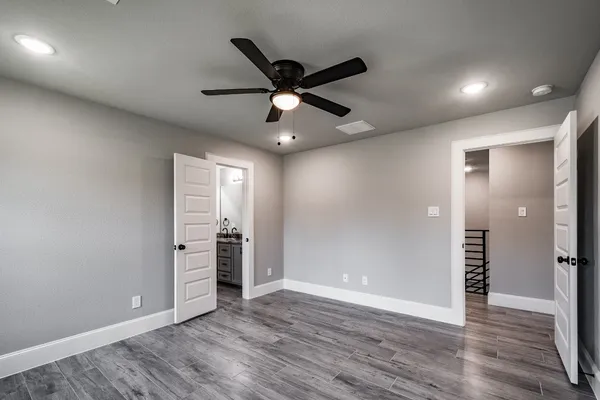 an empty room with wooden floor and a ceiling fan