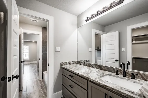 a bathroom with a granite countertop sink and a mirror