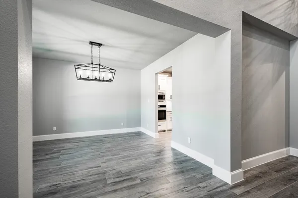 a view of a hallway with wooden floor and chandelier