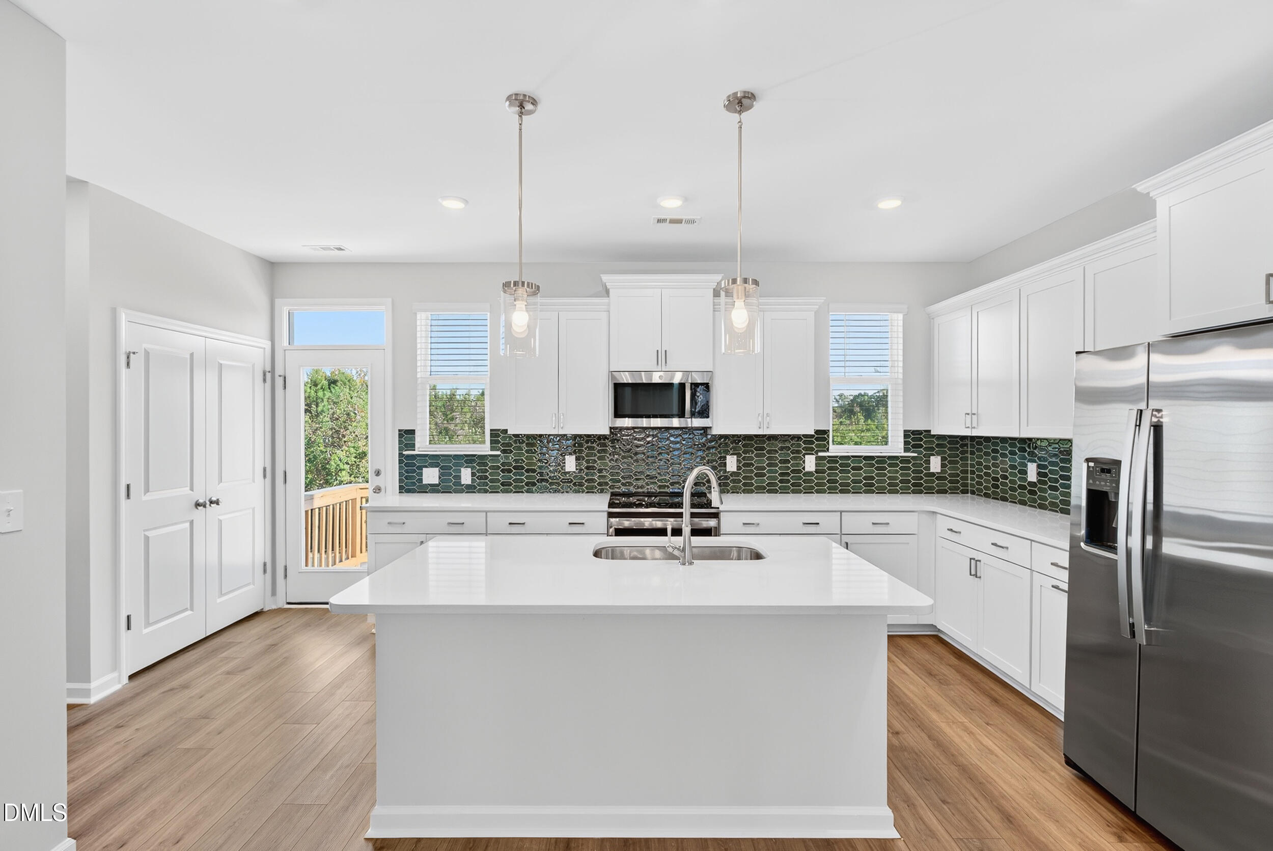 331 Chesapeake Commons Street Garner, NC 27529 - Photo 6 of 20 a kitchen with stainless steel appliances a refrigerator a stove a sink and white cabinets with wooden floor