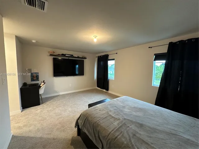 a bedroom with a bed and a flat tv screen on wall