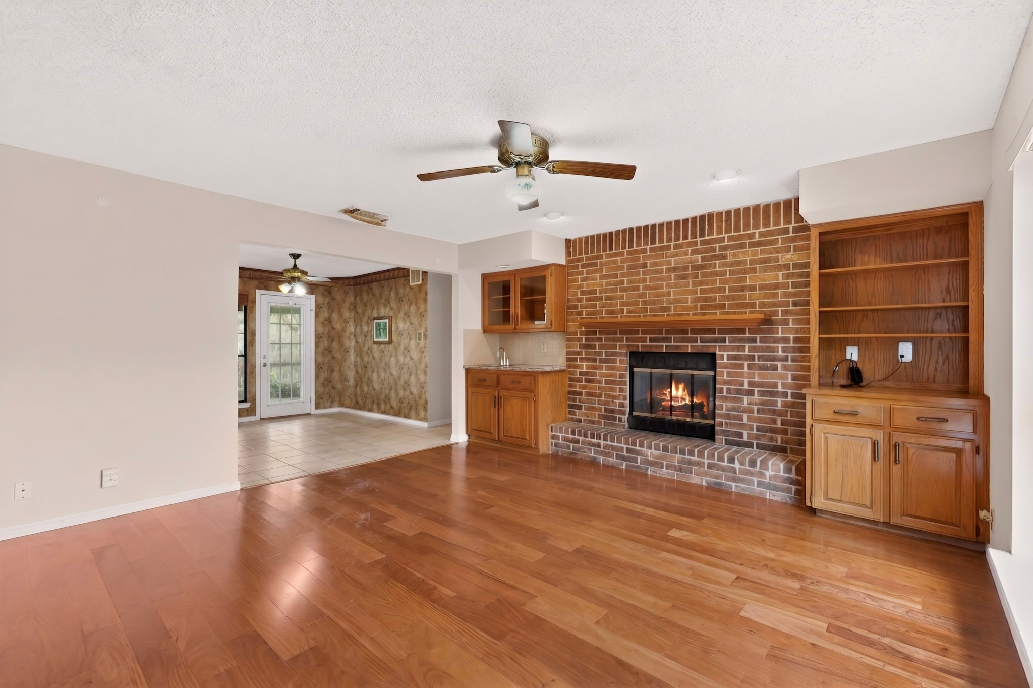 1003 Pier Branch Road Dripping Springs, TX 78620 - Photo 15 of 40 Warm wood floors and a brick fireplace create an inviting living space, complete with a convenient wet bar.