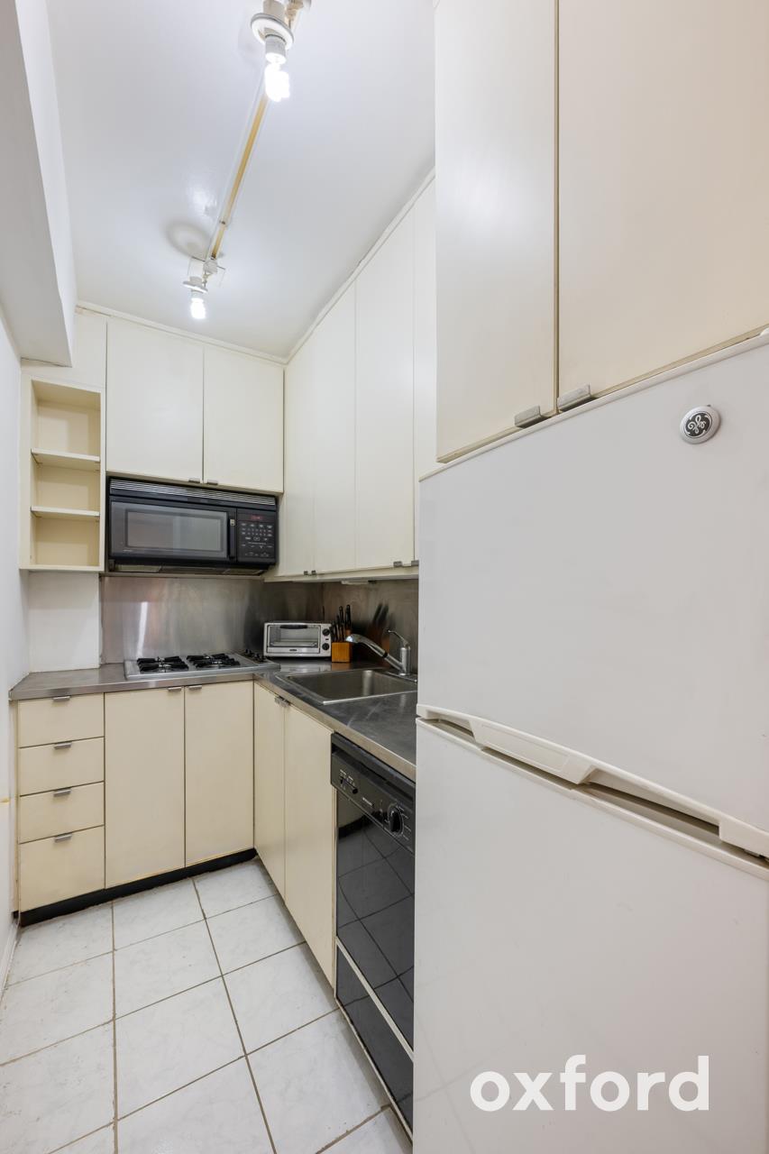 Undisclosed Address Manhattan, NY 10019 - Photo 7 of 20 a kitchen with white cabinets and white appliances